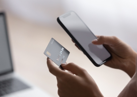 Person holding cell phone and debit card