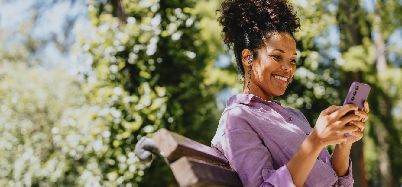 Woman sitting on park bench looking at smartphone